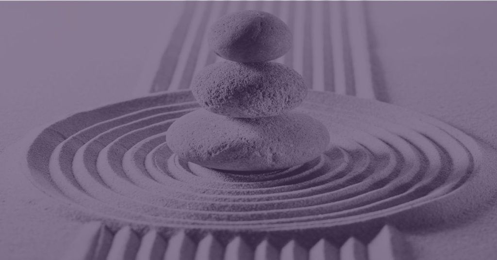 Stacked stones in a raked sand garden with a purple overlay — stillness and intentional rest after a season of momentum